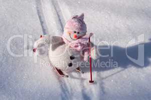 Textile snowman with snow slides down hill skiing