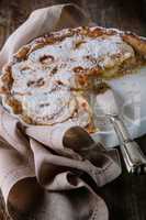 Apple pie with the knife on wooden table.