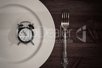 Vintage clocks lie in a white plate, next is fork