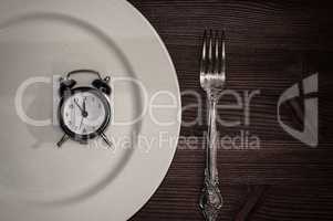 Vintage clocks lie in a white plate, next is fork
