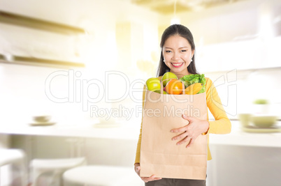 Woman holding groceries bag in kitchen