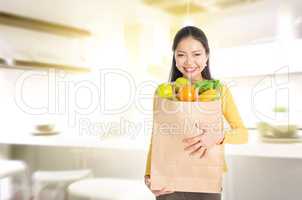 Woman holding groceries bag in kitchen
