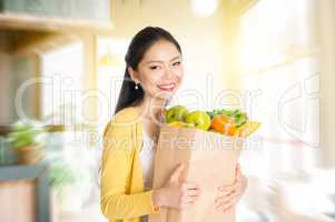 Asian woman holding groceries bag in market