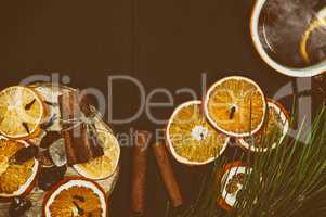 cup of hot tea with slices of lemon and orange on a black wooden
