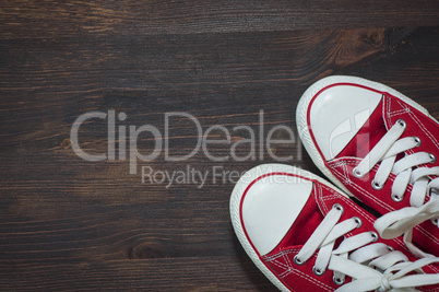 pair of red sneakers on a brown wooden surface