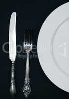 Half empty white plates, vintage knife and fork on  table