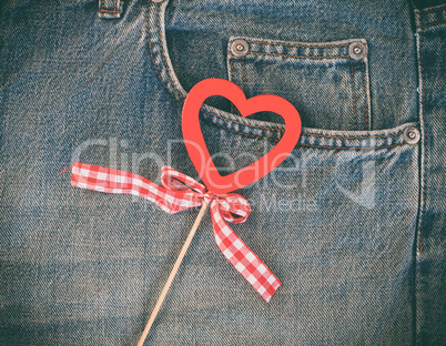 Red wooden heart on a background of blue worn jeans