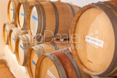 Wine Barrels and Bottles Age Inside Dark Cellar.