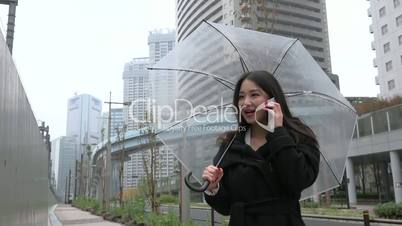 Beautiful Asian Woman Talking On Mobile Phone With Umbrella