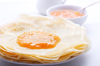 Crispy crepes with apricot jam served on a table.