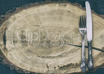 Fork and knife on a brown wooden stump, empty space