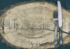 Fork and knife on a brown wooden stump, empty space
