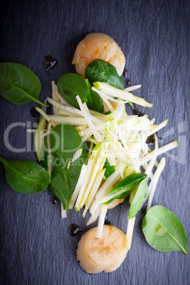 Scallop salad with apple, spinach on a stone plate.
