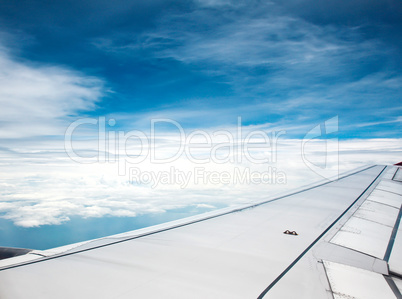 Blue sky and cloubs view over the wing of the plane.