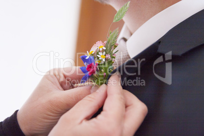 Ansteckblume wird dem Braeutigam angesteckt