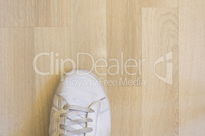 White sneaker shoe on wooden floor