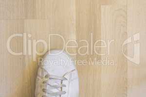 White sneaker shoe on wooden floor