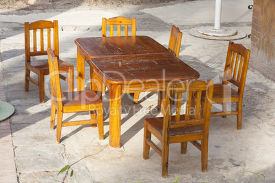 Outdoor cafe patio with old, shabby wooden tables and chairs in the sunlight photo
