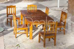 Outdoor cafe patio with old, shabby wooden tables and chairs in the sunlight photo