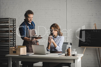 Man showing pastries to young woman