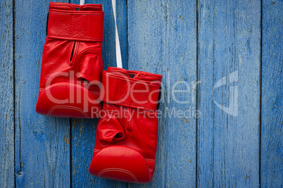 Red leather boxing gloves hanging on a rope