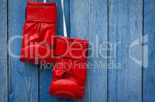 Red leather boxing gloves hanging on a rope