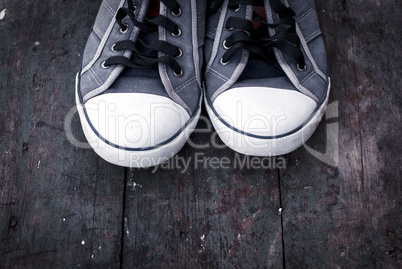 old man's worn sneakers on a wooden surface
