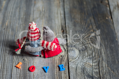 Two small wooden man sitting in an embrace on gray wooden backgr