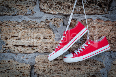 pair of red sneakers sport on the background wall with brickwork