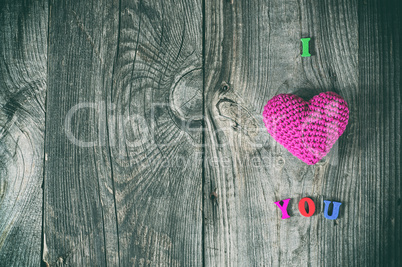 Abstract gray background with wooden sign and a red knitted hear