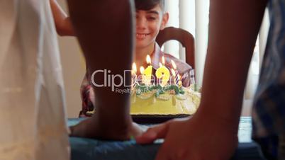 Birthday Party With Happy Latino Boy Blowing Candles On Cake