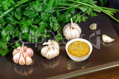 Parsley leaves and garlic on the surface of the table.