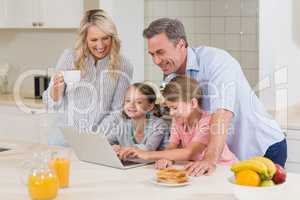 Family using laptop while having breakfast in kitchen