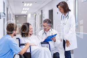 Doctors interacting with pregnant woman in corridor