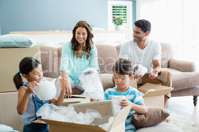 Parents and kids unpacking carton boxes in living room