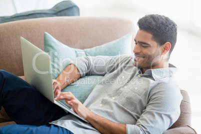 Man sitting on sofa and using laptop in living room