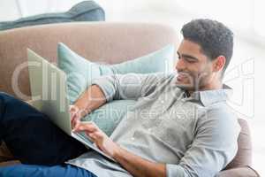 Man sitting on sofa and using laptop in living room