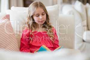 Girl reading a book on sofa in living room