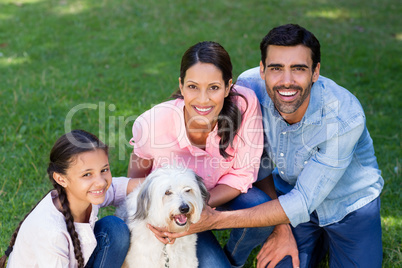 Happy family enjoying together with their pet dog in park