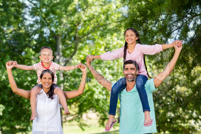 Portrait of parents carrying their children on shoulder in park