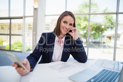 Businesswoman sitting at desk and using mobile phone