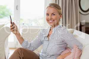 Smiling beautiful woman holding mobile phone in living room