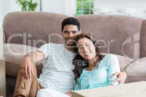 Happy couple sitting with arm around in living room