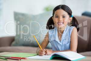 Portrait of girl doing her homework in living room