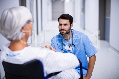 Male doctor interacting with senior patient on wheelchair