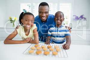 Portrait of father and kids with cookies on table