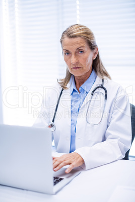 Portrait of female doctor using laptop