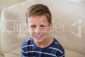 Smiling cute boy sitting on sofa in living room