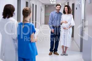 Happy couple interacting with doctors in corridor