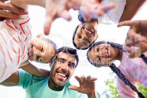 Portrait of happy family forming huddle in park